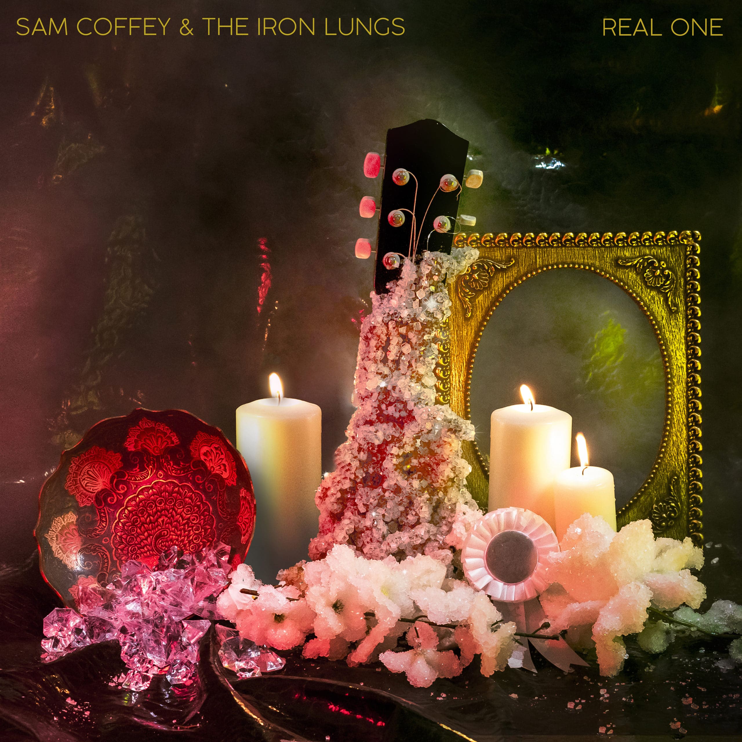 Cover for Sam Coffey and the Iron Lungs album 'Real One'. A guitar neck encrusted with diamonds surrounded by flowers and candles. Dimly lit.
