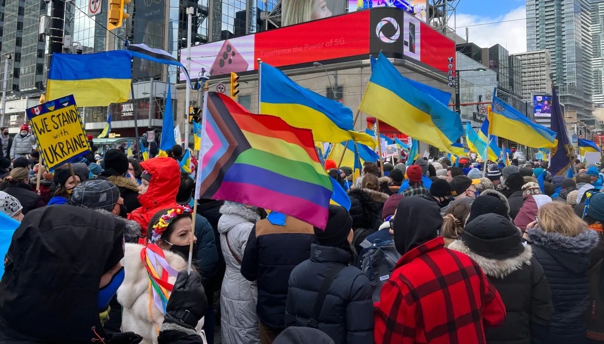 A pride flag waving amidst Ukrainian flags at a protest